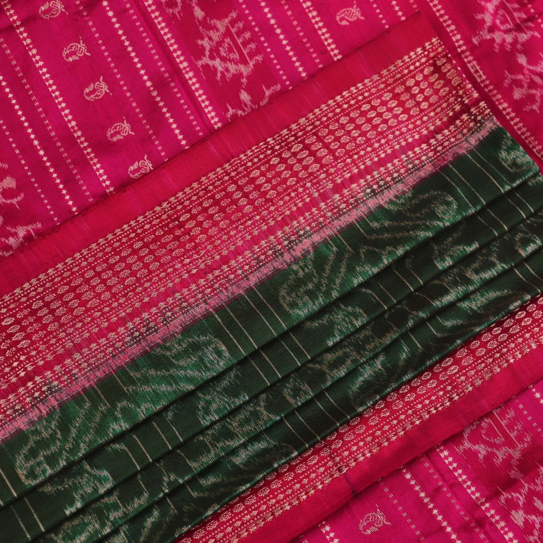 Close-up of textured green Sambalpuri silk saree fabric with magenta motifs.