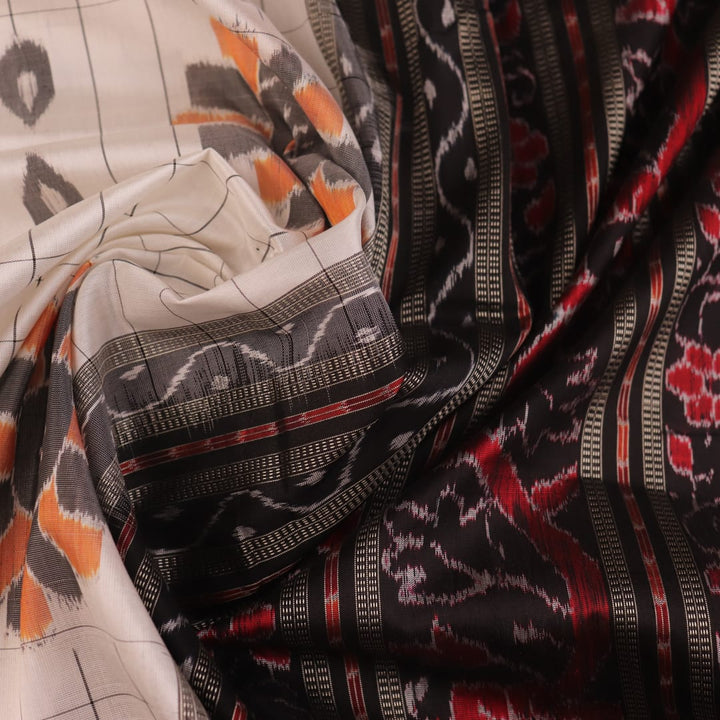 Close-up of handloom Sambalpuri silk saree fabric texture; white with subtle black motifs.