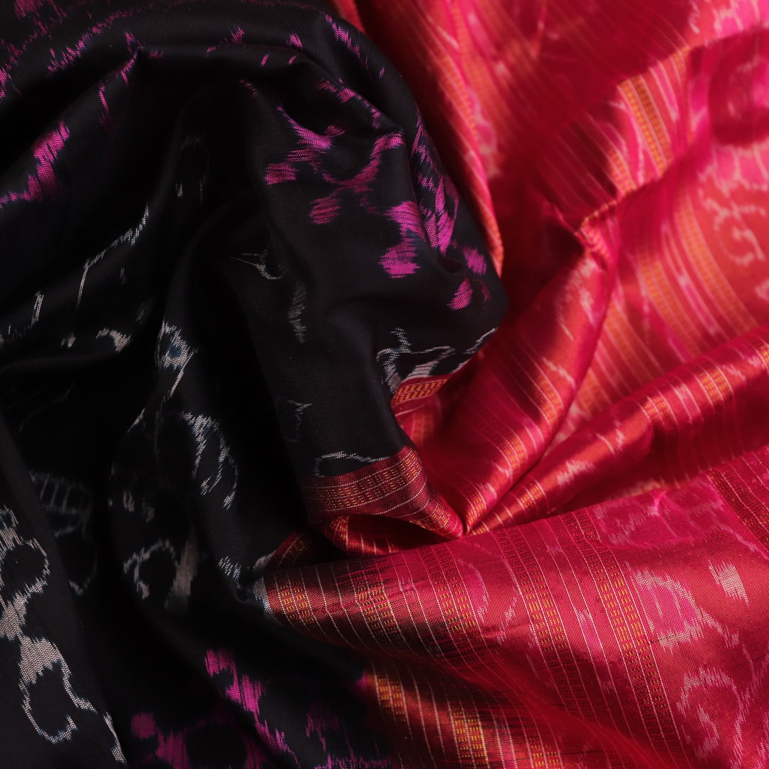 Close-up of black Sambalpuri silk saree fabric texture with subtle motifs and magenta threads.