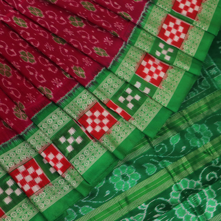 Close-up of magenta Sambalpuri silk saree fabric texture, showcasing intricate handloom weave and subtle motifs.