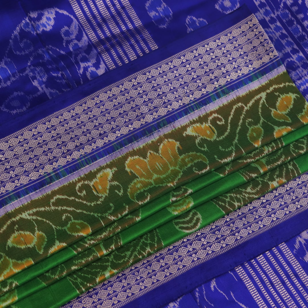 Close-up of green and blue Sambalpuri silk saree fabric showing intricate handloom weave and motif details.