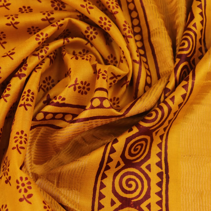 Close-up of the yellow printed Tussar silk saree's distinct slubby fabric texture.