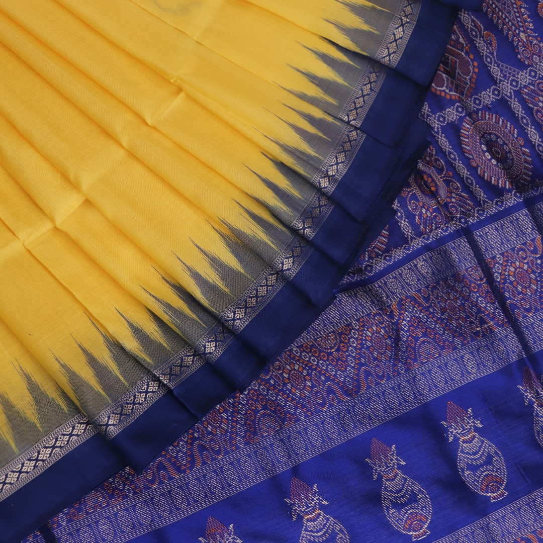 Textured close-up of yellow Bomkai silk saree fabric with blue butta pattern.