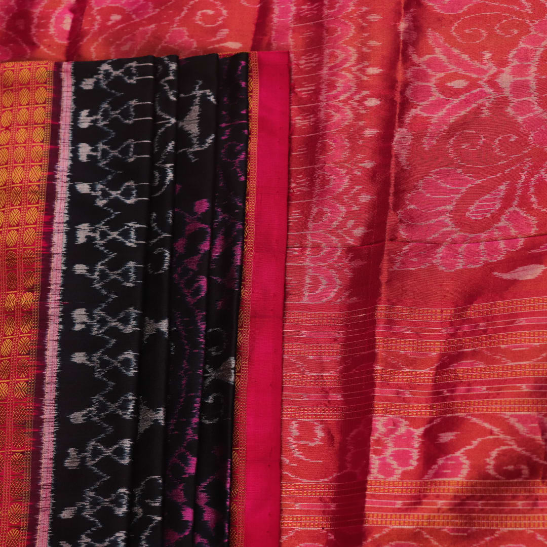 Close-up of black Sambalpuri silk saree fabric texture with subtle motifs and magenta threads.