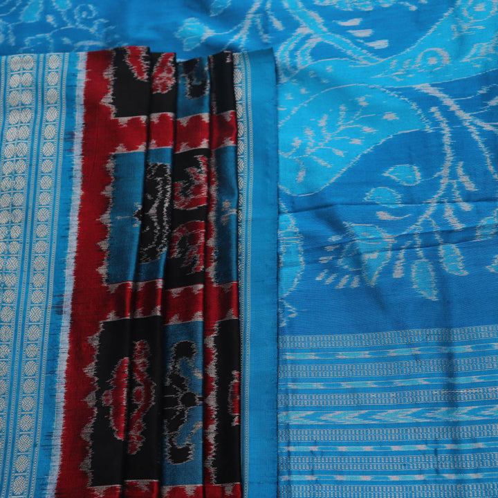 Close-up of multi-color Sambalpuri silk saree fabric showing texture and woven motifs; secondary color blue visible.