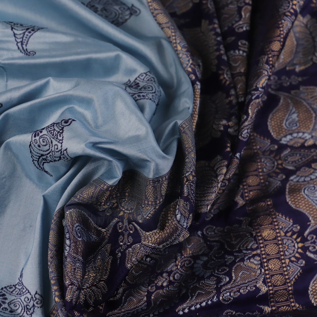 Close-up fabric texture of a blue Bomkai silk saree, revealing intricate butta pattern weave.