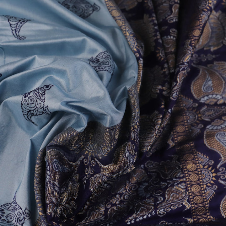 Close-up fabric texture of a blue Bomkai silk saree, revealing intricate butta pattern weave.