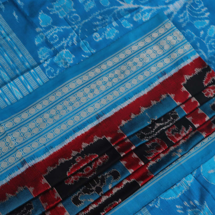 Close-up of multi-color Sambalpuri silk saree fabric showing texture and woven motifs; secondary color blue visible.