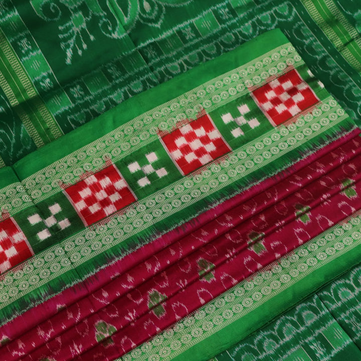 Close-up of magenta Sambalpuri silk saree fabric texture, showcasing intricate handloom weave and subtle motifs.