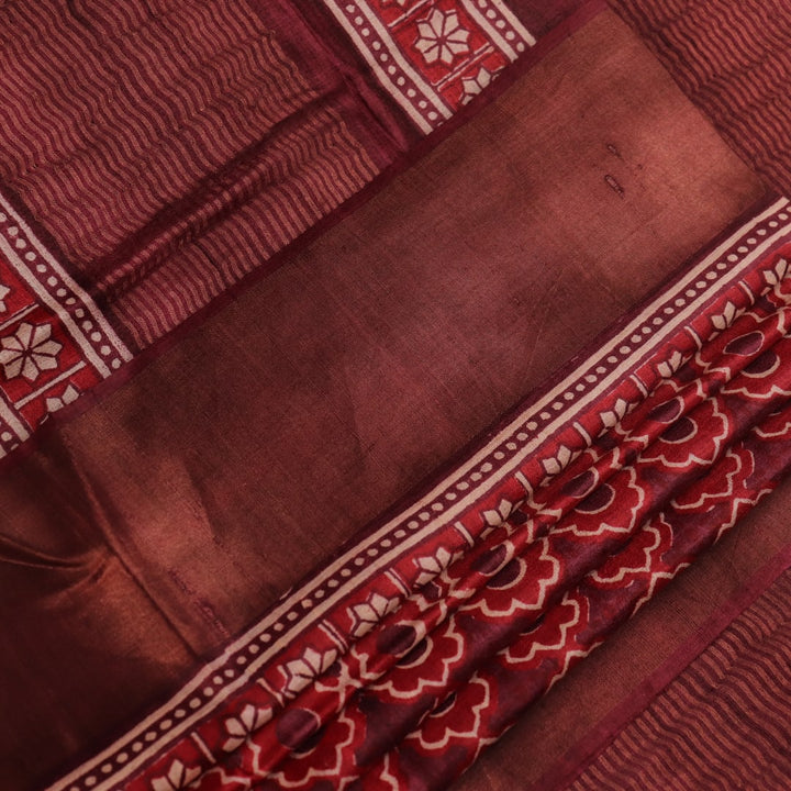 Close-up of maroon Tussar silk saree fabric, revealing its characteristic slub texture and printed details.