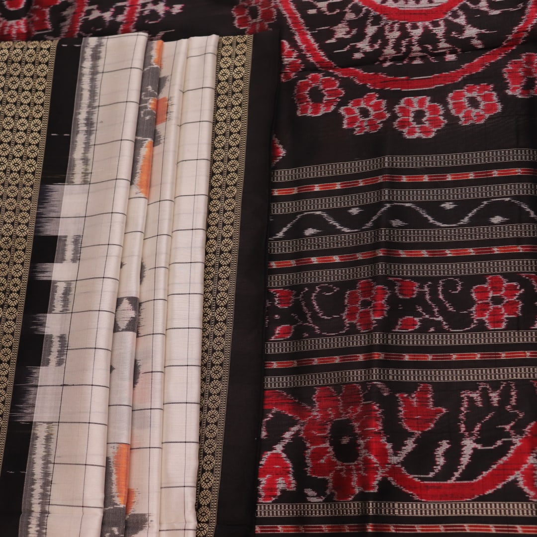 Close-up of handloom Sambalpuri silk saree fabric texture; white with subtle black motifs.