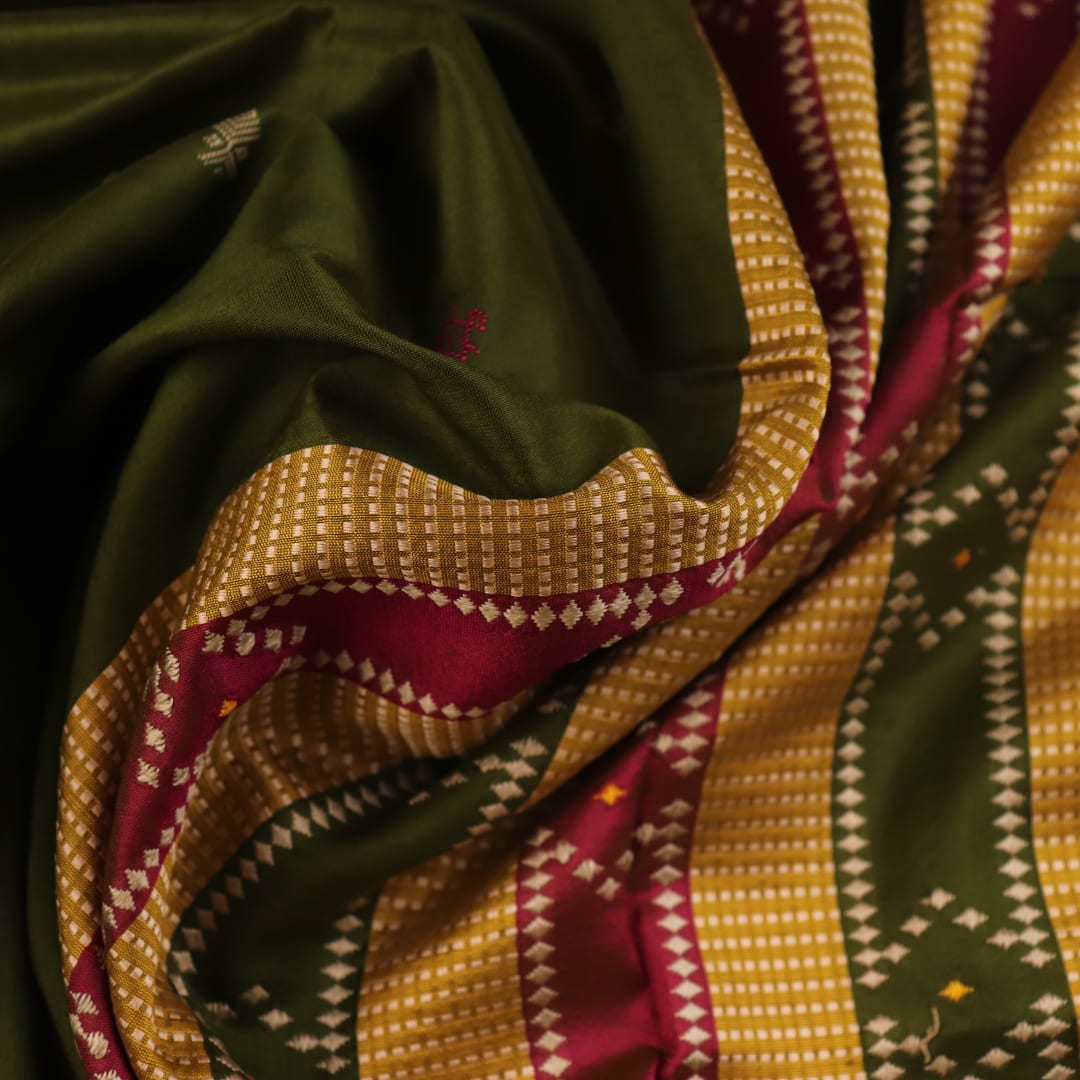 Close-up of the textured green Sambalpuri Silk Saree fabric, highlighting the woven butta pattern.