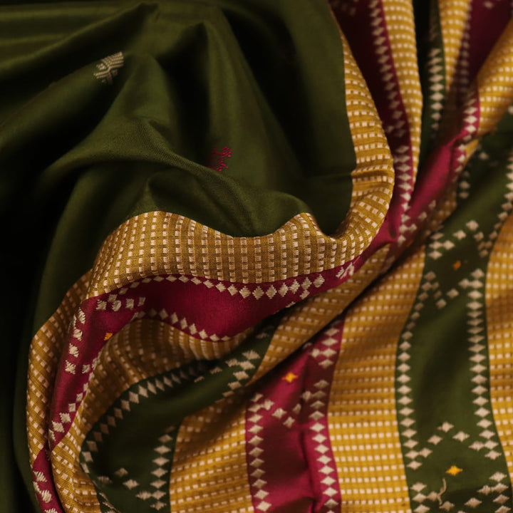 Close-up of the textured green Sambalpuri Silk Saree fabric, highlighting the woven butta pattern.