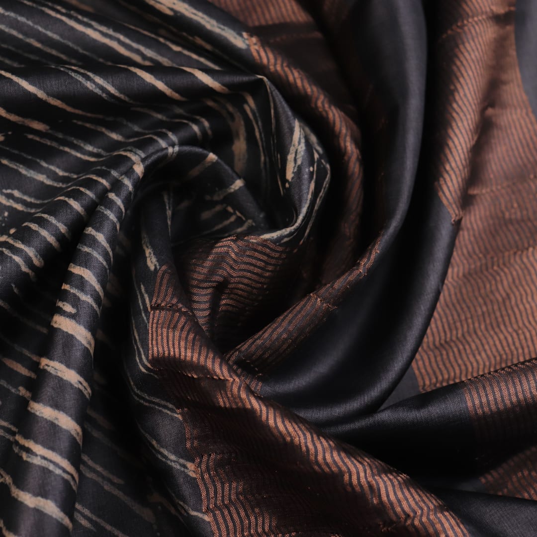 Close-up of the natural slub texture of grey printed Tussar silk saree fabric.