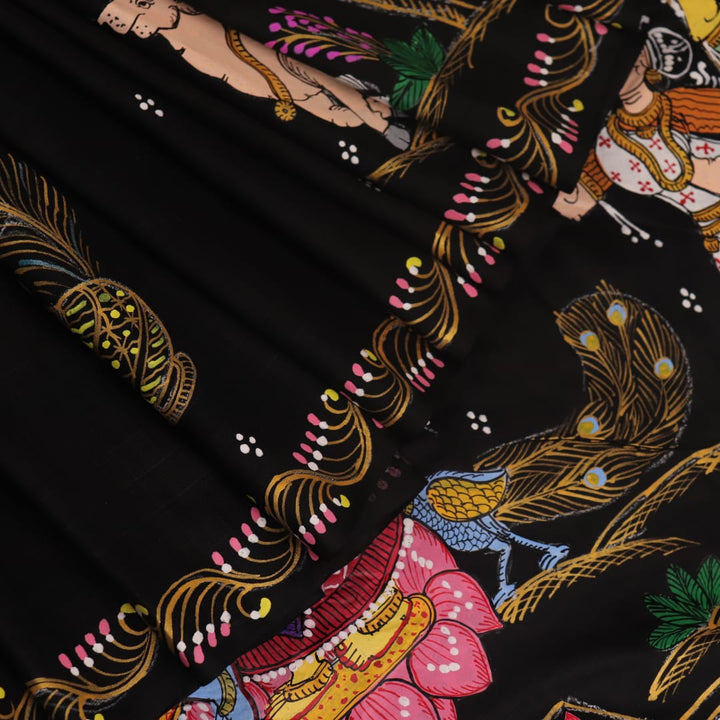 Close-up of black silk Patachitra saree fabric texture showing hand-painted details.