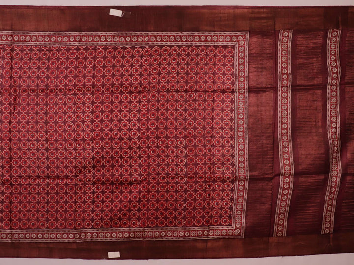 Close-up of maroon Tussar silk saree fabric, revealing its characteristic slub texture and printed details.