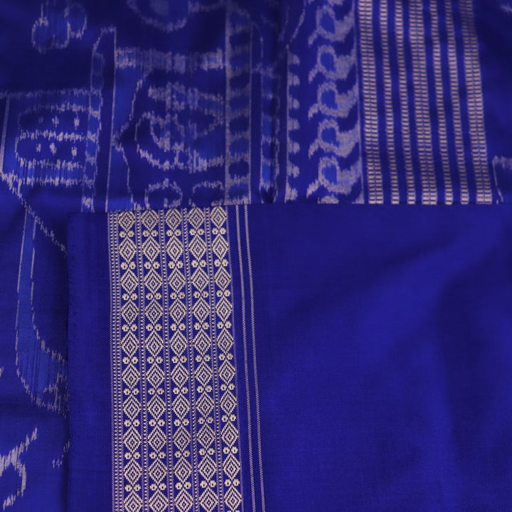 Close-up of green and blue Sambalpuri silk saree fabric showing intricate handloom weave and motif details.