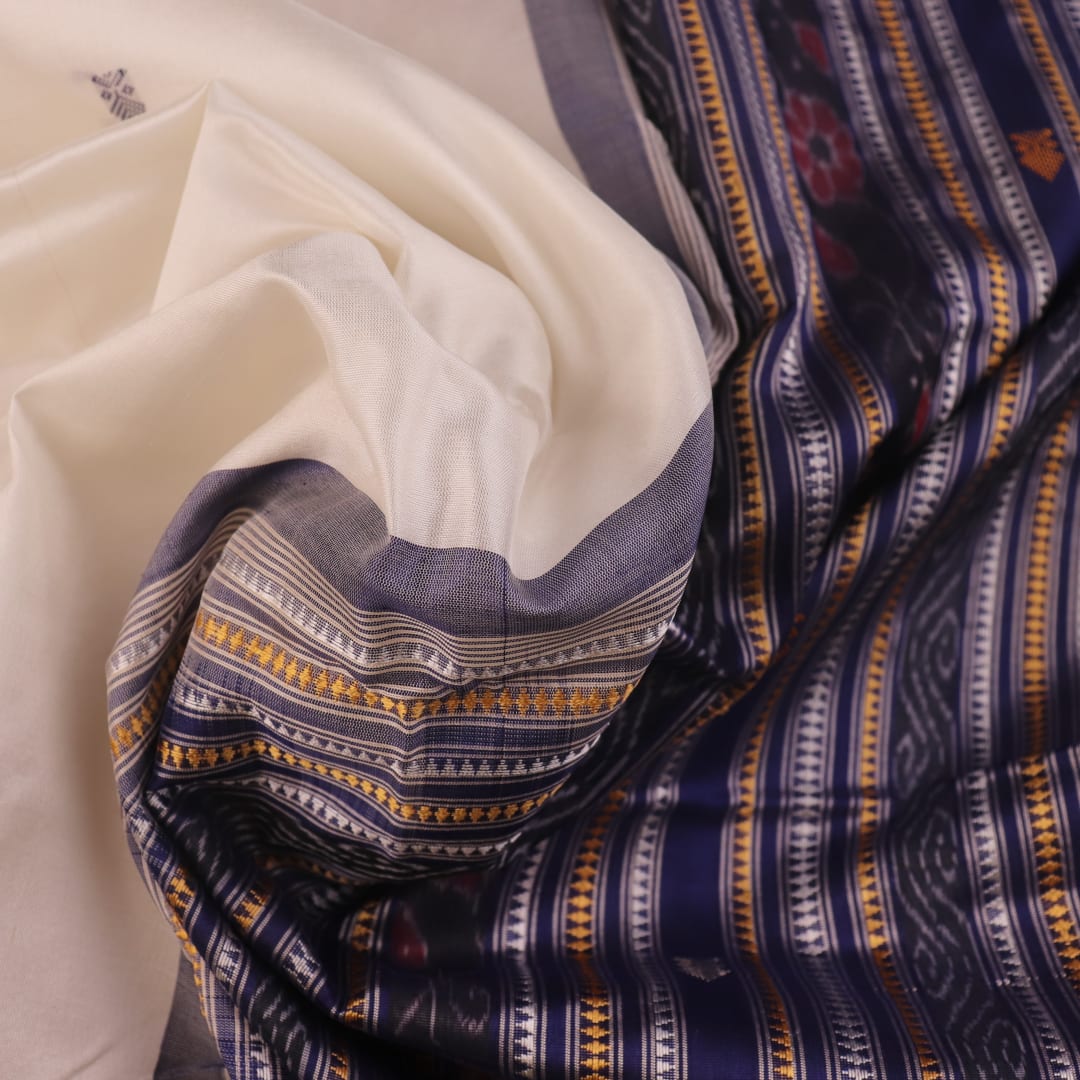 Close-up of white and blue Sambalpuri Silk Saree fabric texture, highlighting butta pattern.