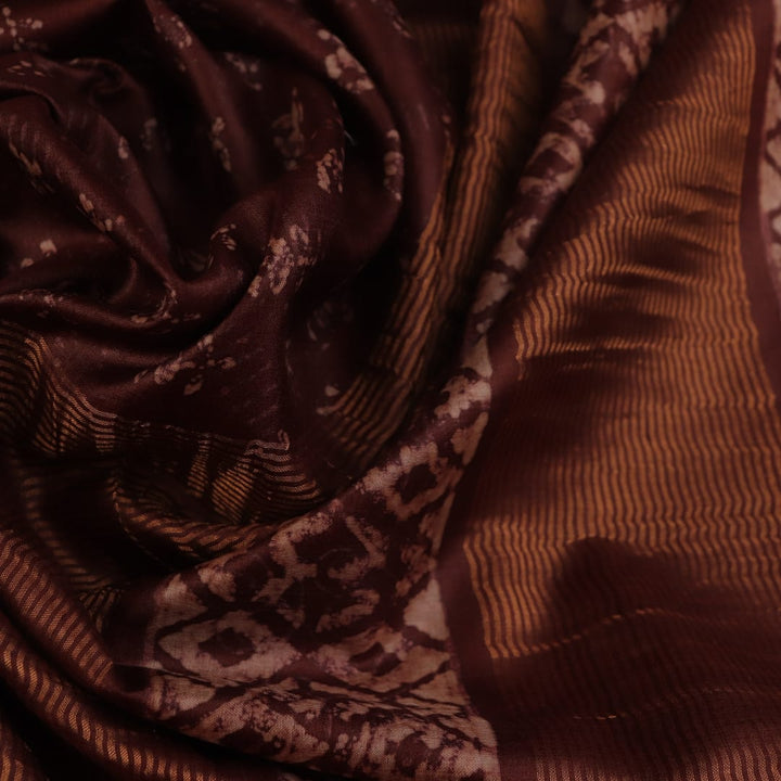 Close-up of the brown Tussar silk saree fabric, highlighting its natural slub texture and printed pattern.