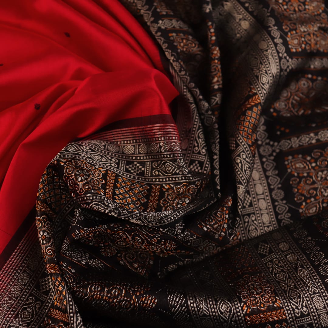 Detailed close-up of the red and black Bomkai silk saree fabric texture, featuring a butta pattern.