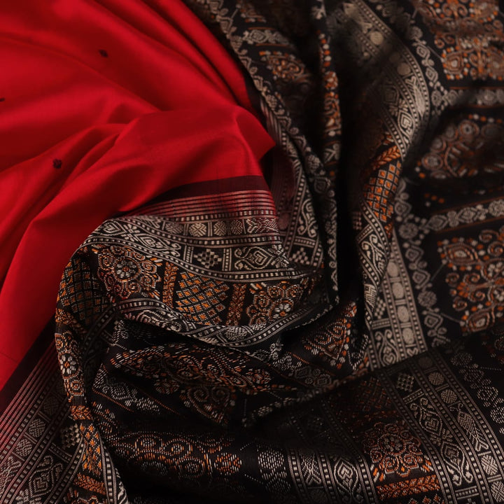 Detailed close-up of the red and black Bomkai silk saree fabric texture, featuring a butta pattern.