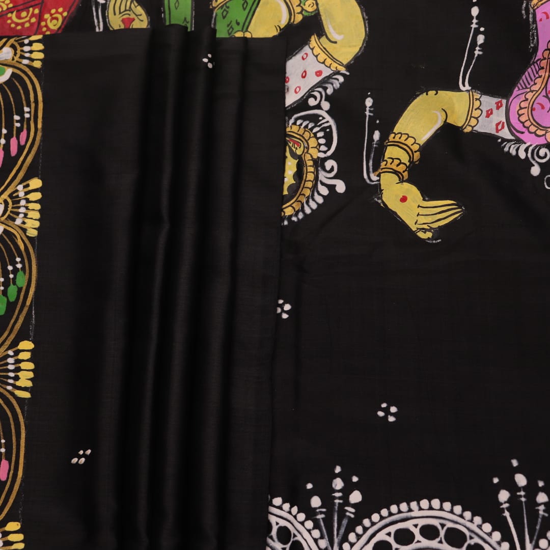 Close-up of black silk Patachitra saree fabric texture showing hand-painted details.