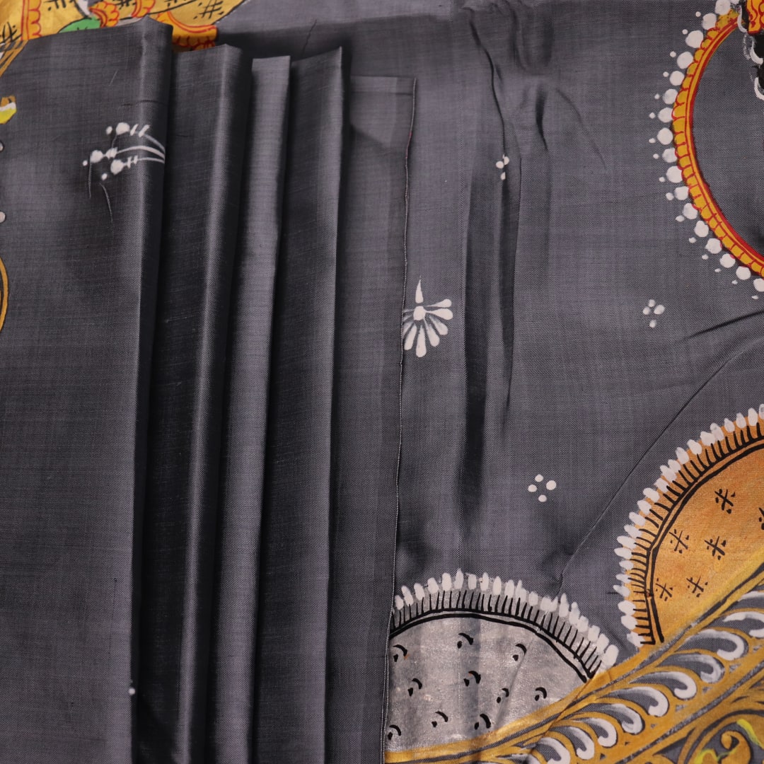 Close-up of handloom grey silk Patachitra saree fabric texture, revealing the intricate details of the hand-painted design.