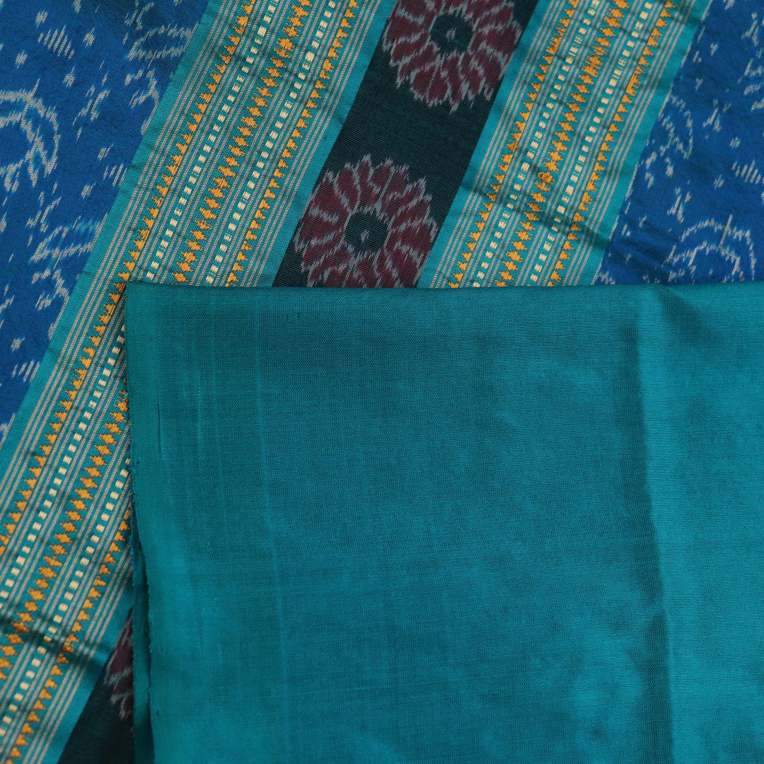 Close-up of the textured weave of a purple Sambalpuri silk saree with green accents and butta pattern.