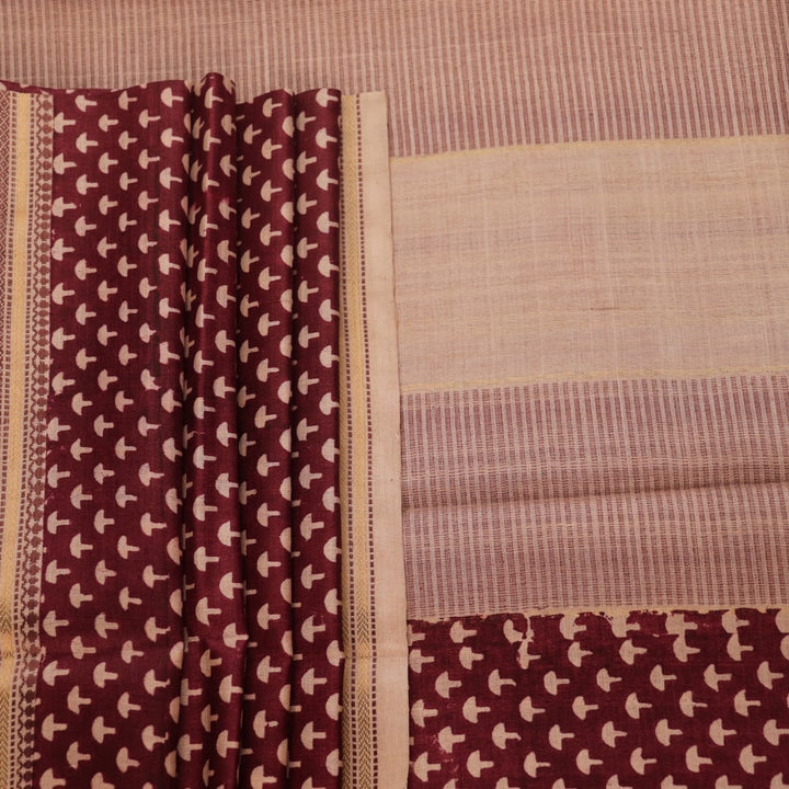 Close-up of maroon Tussar silk saree fabric, showing natural slub texture and printed pattern.