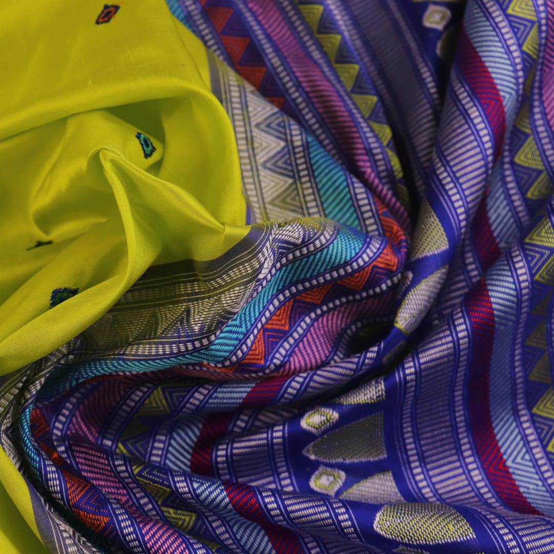 Close-up of green and blue Dongria silk saree fabric texture with butta pattern.