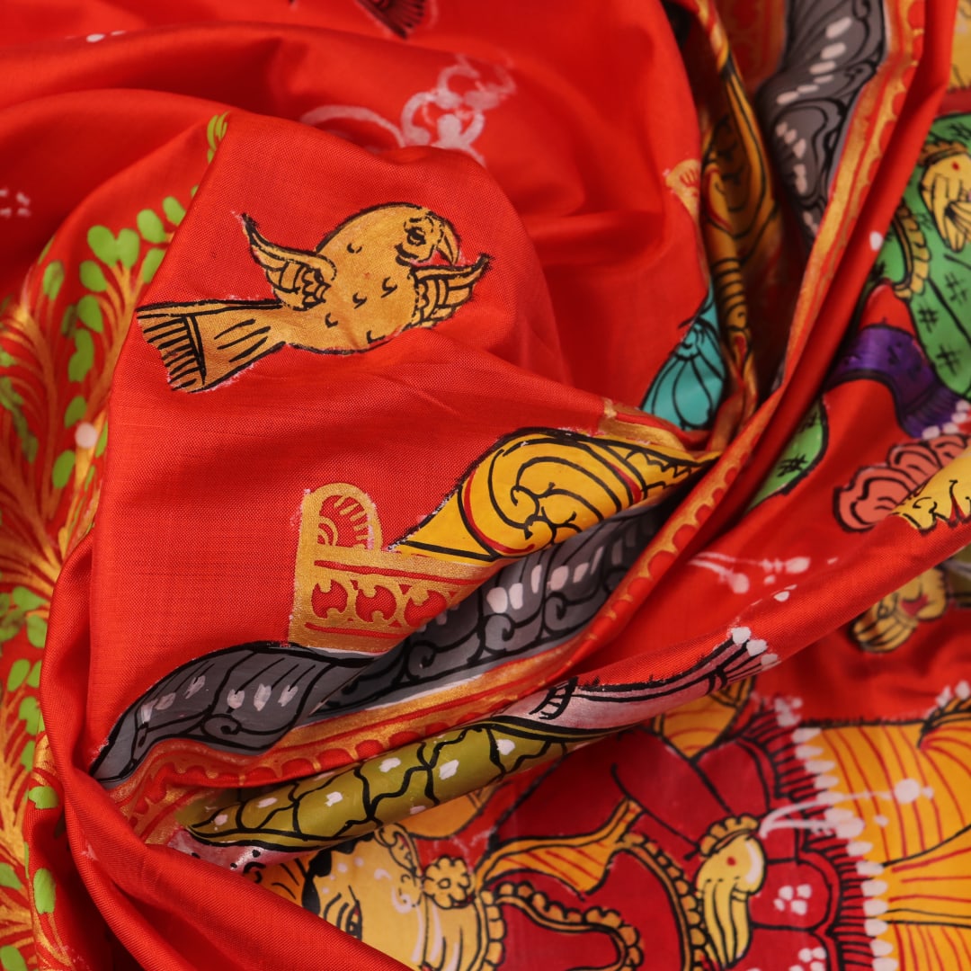 Close-up of red Patachitra silk saree fabric showing hand-painted texture.