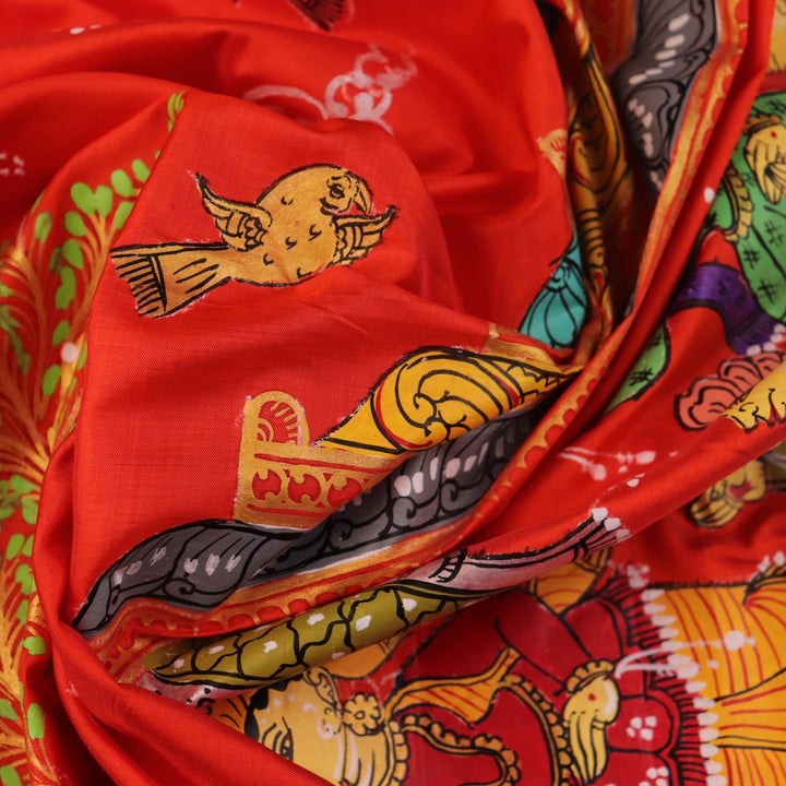 Close-up of red Patachitra silk saree fabric showing hand-painted texture.