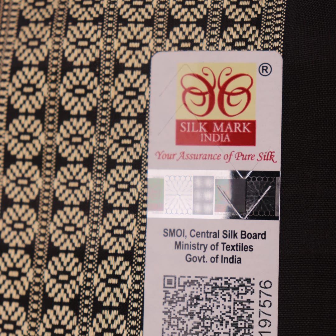 Close-up of handloom Sambalpuri silk saree fabric texture; white with subtle black motifs.