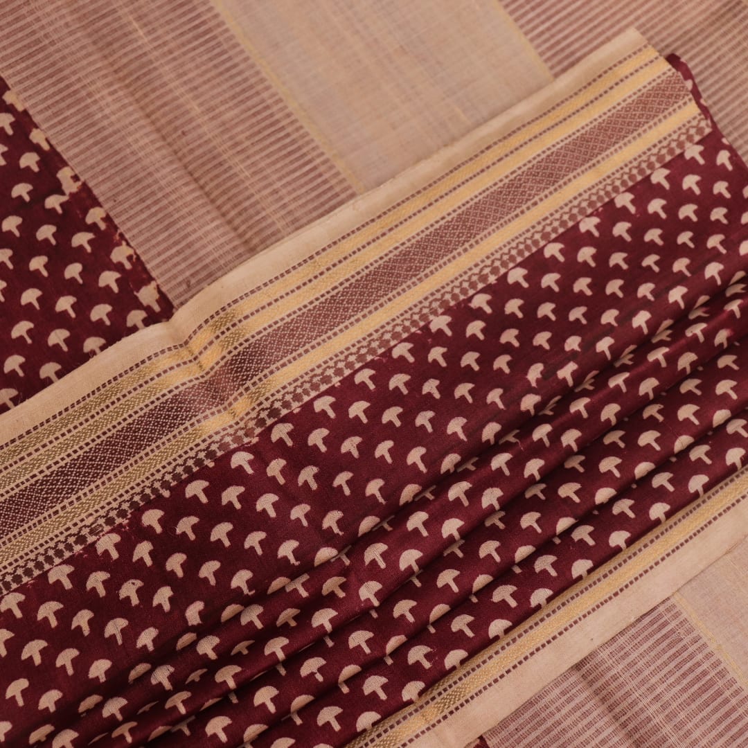 Close-up of maroon Tussar silk saree fabric, showing natural slub texture and printed pattern.