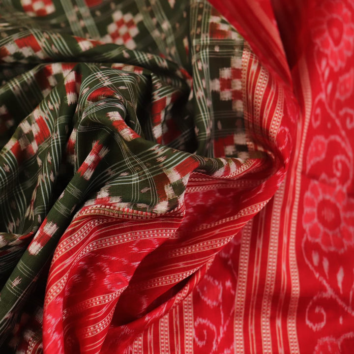 Close-up of green Sambalpuri silk saree fabric showing intricate woven motif texture and red thread details.