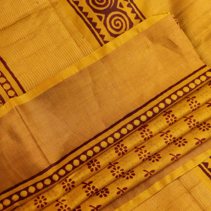Close-up of the yellow printed Tussar silk saree's distinct slubby fabric texture.