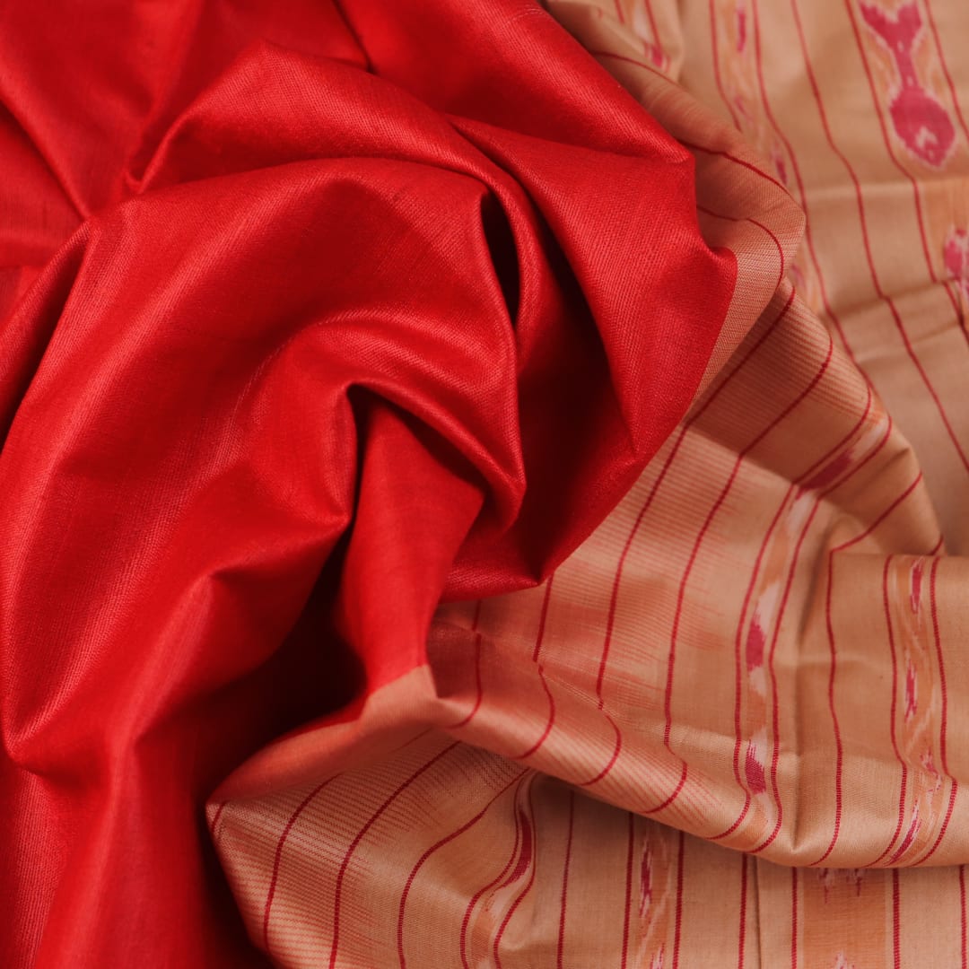Close-up of plain red and off-white Tussar silk saree fabric texture.