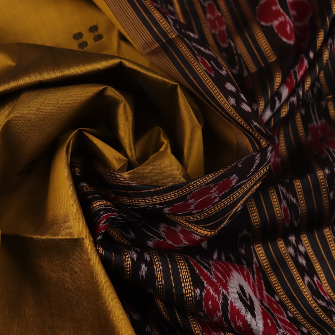 Green and black Khandua silk saree draped; showcasing its butta pattern and elegant fall.