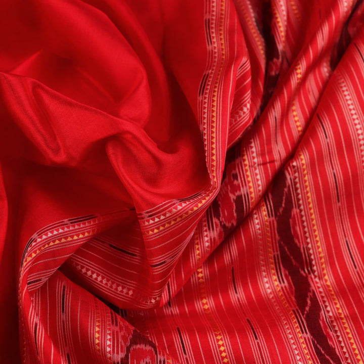 Close-up of the distinct handwoven texture of a red Sambalpuri silk saree with Butta pattern.