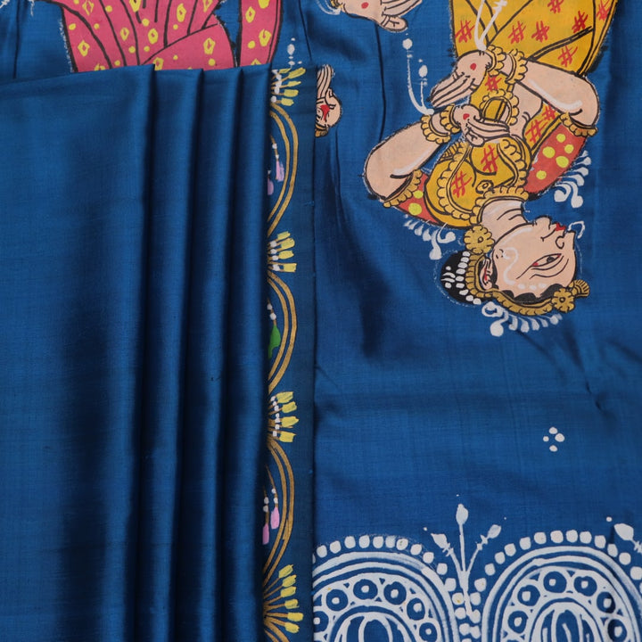 Close-up of handloom blue silk Patachitra saree fabric, showcasing the fine texture and hand-painted details.