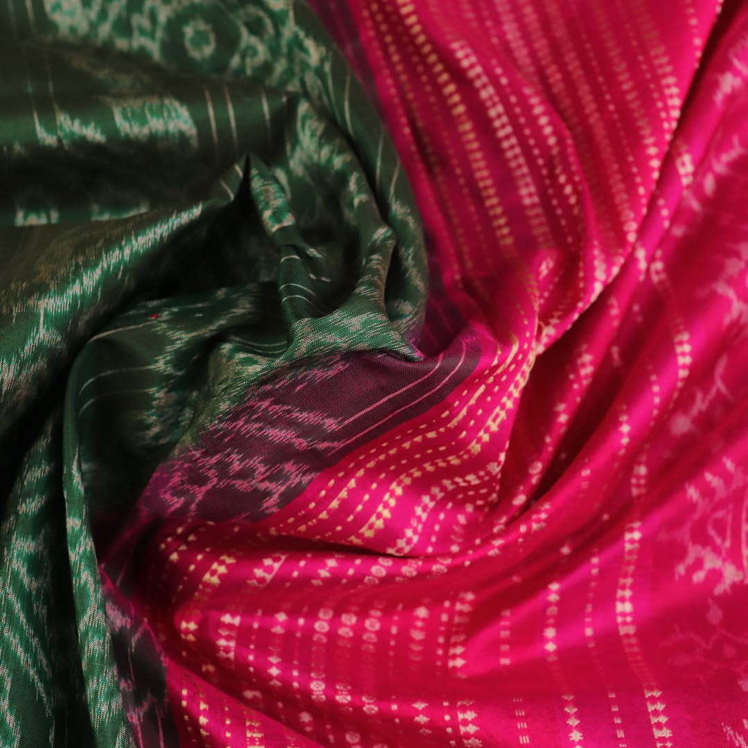 Close-up of textured green Sambalpuri silk saree fabric with magenta motifs.