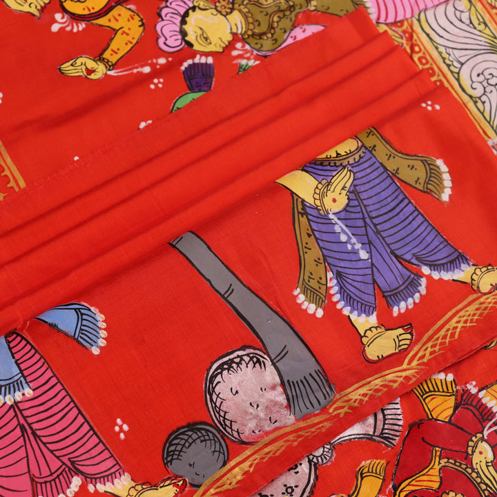 Close-up of red Patachitra silk saree fabric showing hand-painted texture.