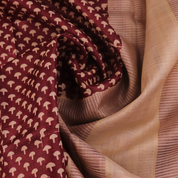 Close-up of maroon Tussar silk saree fabric, showing natural slub texture and printed pattern.