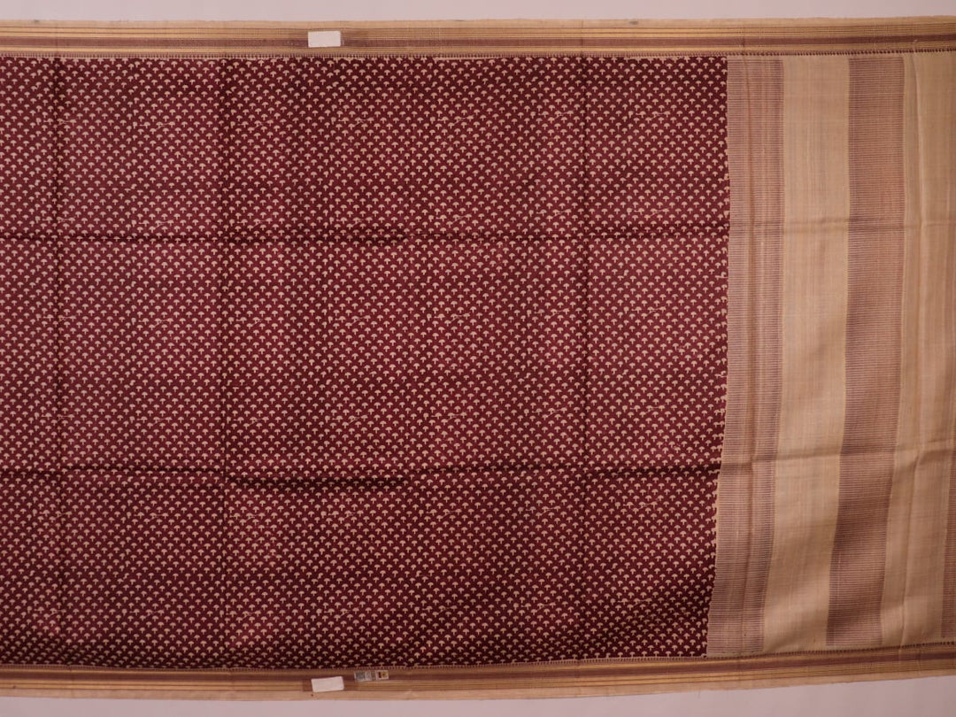 Close-up of maroon Tussar silk saree fabric, showing natural slub texture and printed pattern.