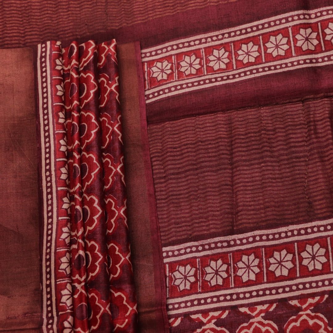 Close-up of maroon Tussar silk saree fabric, revealing its characteristic slub texture and printed details.