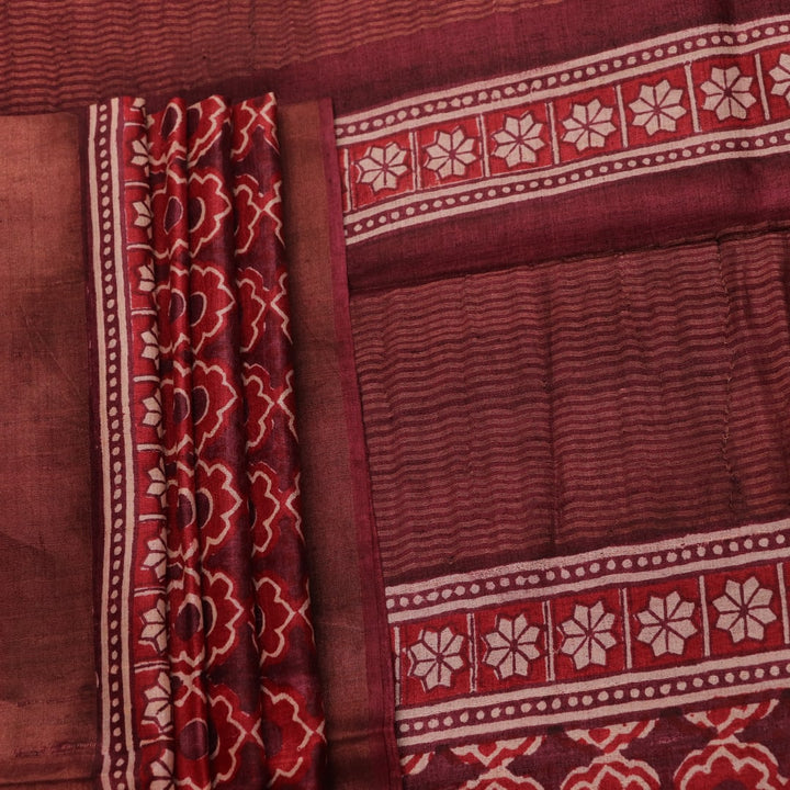 Close-up of maroon Tussar silk saree fabric, revealing its characteristic slub texture and printed details.