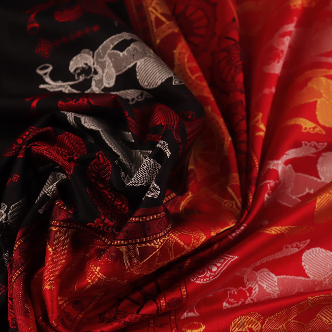 Close-up of Bomkai silk saree fabric texture in black and red, detailing the woven butta pattern.