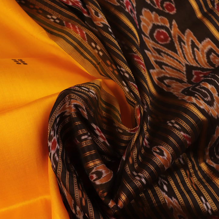 Model showcasing yellow Khandua silk saree with black butta pattern.
