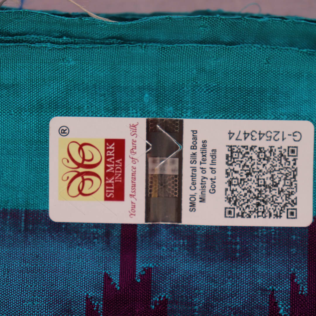 Close-up of the textured weave of a purple Sambalpuri silk saree with green accents and butta pattern.