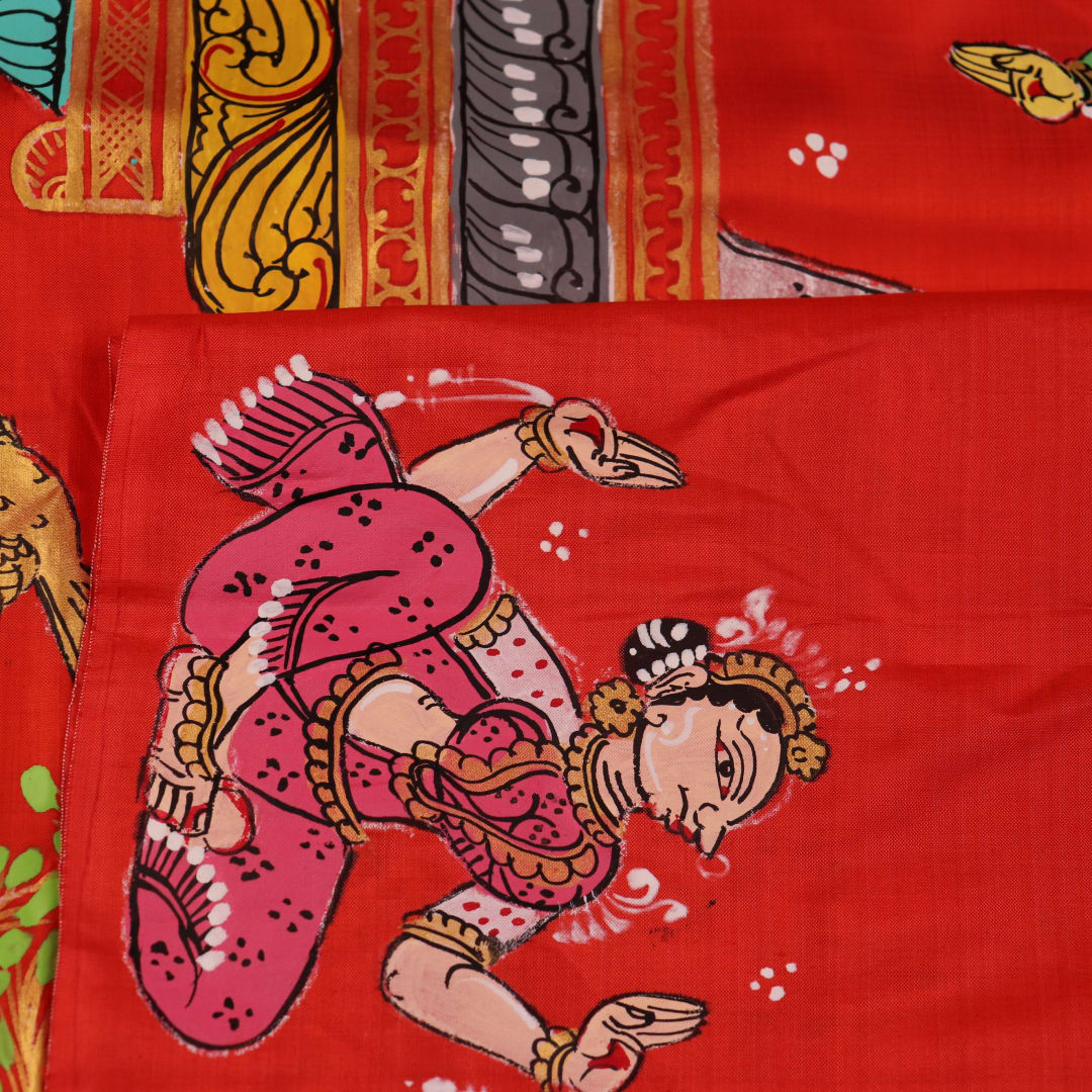Close-up of red Patachitra silk saree fabric showing hand-painted texture.